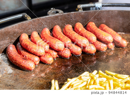 Delicious sausages from meat on a large metal pan grilling over hot coals Delicious sausages from meat on a large metal pan grilling over hot coals 94844814