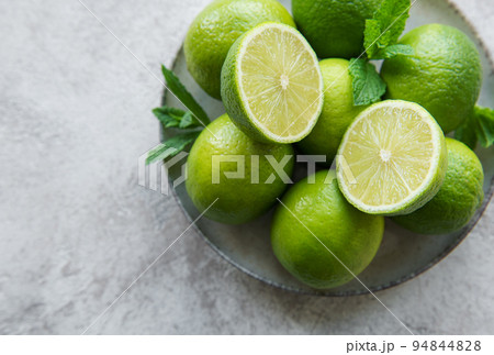 Green  Limes with fresh mint leaves on  plate 94844828