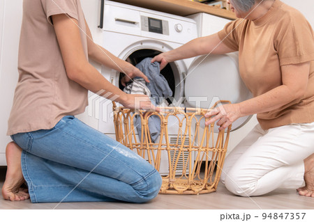 Contented daughter and mother in the household washing room working together. Contented daughter and mother in the household washing room working together. 94847357