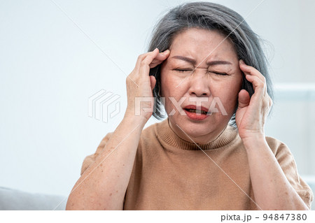 An agonizing senior woman with a headache in her contented environment. An agonizing senior woman with a headache in her contented environment. 94847380