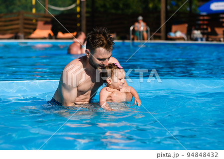 Father teach baby to swim in pool Father teach baby to swim in pool 94848432