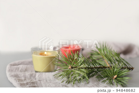 winter holiday or weekend ambient still life. glowing soy wax candles in glass pots and pine tree needles on soft textile tablecloth. cozy home, calm and peaceful decor for fall season winter holiday or weekend ambient still life. glowing soy wax candles in glass pots and pine tree needles on soft textile tablecloth. cozy home, calm and peaceful decor for fall season 94848682