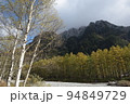 長野県安曇野市の上高地にある秋から冬ごろの梓川の六百山方向の林の紅葉と雪山と青空 94849729