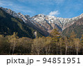 長野県安曇野市の上高地にあるバスターミナル付近の散策路で観られる西穂高方向の紅葉と雪山と青空 94851951