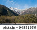 長野県安曇野市の上高地にあるバスターミナル付近の散策路で観られる西穂高方向の紅葉と雪山と青空 94851956
