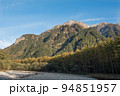 長野県安曇野市の上高地にあるバスターミナル付近の散策路で観られる六百山方向の紅葉と雪山と青空 94851957