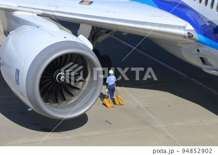 旅客機の車輪止めを運ぶグランドクルー　到着した旅客機 94852902
