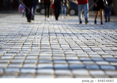 people cross the road at a pedestrian crossing on the pavement in a blurred focus 94854665