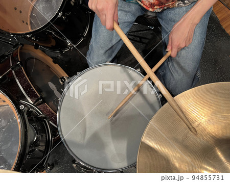 音楽スタジオにあるドラムセットとスティックで演奏する手 94855731