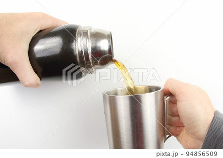tea is poured into a mug of thermos 94856509