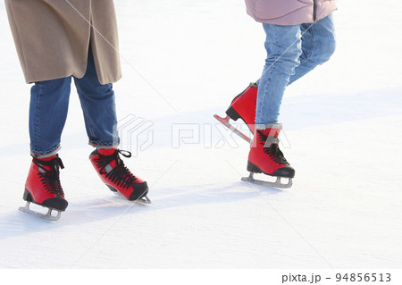 Feet of people skating on a street ice rink 94856513
