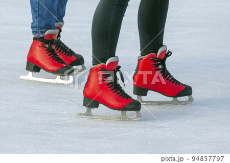 feet in red skates on an ice rink. Hobbies and sports. Vacations and winter activities. feet in red skates on an ice rink. Hobbies and sports. Vacations and winter activities. 94857797