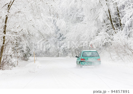 green car on a snowy road, Orlicke Mountains, Czech Republic 94857891