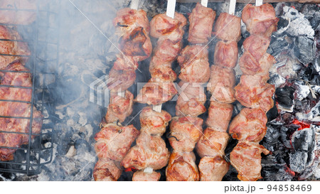 Delicious grilled pork meat in BBQ Barbecue with pork meat. Kebabs on the grill. Close-Up Of Meat On Barbecue Grill With Smoke. 94858469