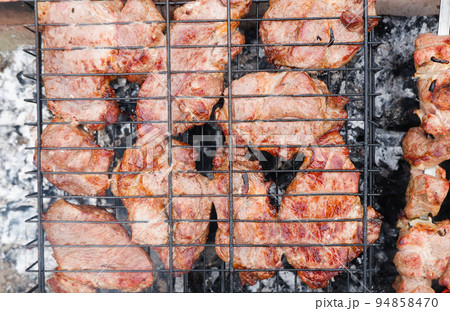 Delicious grilled pork meat in BBQ Barbecue with pork meat. Kebabs on the grill. Close-Up Of Meat On Barbecue Grill With Smoke. Delicious grilled pork meat in BBQ Barbecue with pork meat. Kebabs on the grill. Close-Up Of Meat On Barbecue Grill With Smoke. 94858470