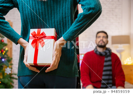 Rear view young caucasian woman hide presents for surprise boyfriend in celebration Christmas. 94859359