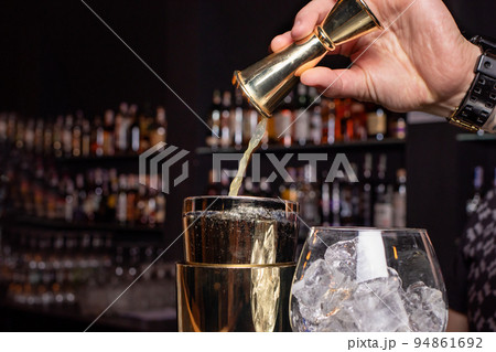 The bartender prepares a cocktail in the restaurant bar. The process of pouring alcohol into a glass. The bartender prepares a cocktail in the restaurant bar. The process of pouring alcohol into a glass. 94861692