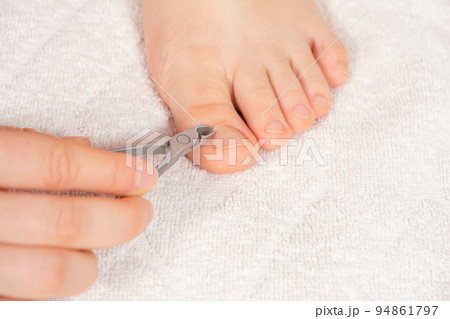 A woman does a pedicure in a beauty salon, removes the cuticle from the big toe with forceps A woman does a pedicure in a beauty salon, removes the cuticle from the big toe with forceps 94861797