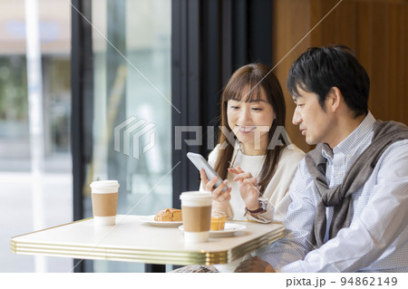 カフェで過ごすミドル夫婦 スマホ 94862149