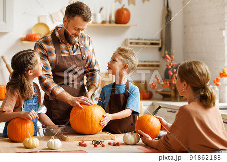 Son and dad making Jack-o-Lantern together at home, carving Halloween pumpkin Son and dad making Jack-o-Lantern together at home, carving Halloween pumpkin 94862183