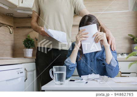 married couple, a man and a woman, are paying bills and utilities, a sad woman is experiencing financial difficulties 94862765