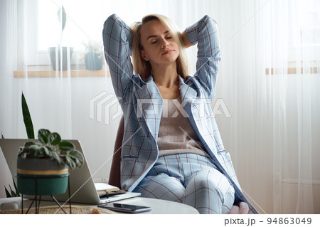 Tired overworked young woman in a suit sitting on a chair in the office Tired overworked young woman in a suit sitting on a chair in the office 94863049