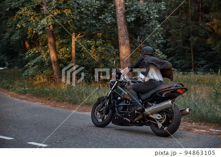Blurred Motion A young man biker in a helmet quickly rides at high speed on a forest road, in motion 94863105