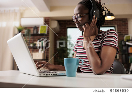 Smiling woman in headphones watching tv series online on laptop, freelancer having break from work. Streaming service, home entertainment, pastime leisure activity concept Smiling woman in headphones watching tv series online on laptop, freelancer having break from work. Streaming service, home entertainment, pastime leisure activity concept 94863650