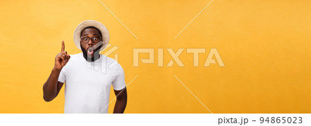 Young african american man over yellow background pointing upwards Young african american man over yellow background pointing upwards 94865023