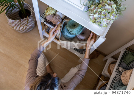Top view woman knitted clothes designer tidying up ribbon yarn needles cupboard storage organization 94871740