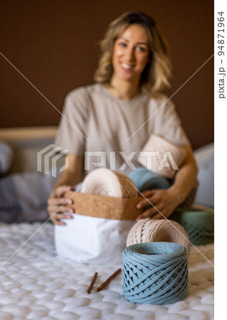 Portrait smiling blonde woman design holding pile of multicolored hank reel ribbon yarn Portrait smiling blonde woman design holding pile of multicolored hank reel ribbon yarn 94871964