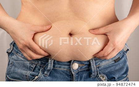 Woman hands pinching her excess belly fat. Obese woman hand holding excessive belly fat, Overweight fatty belly of woman Woman hands pinching her excess belly fat. Obese woman hand holding excessive belly fat, Overweight fatty belly of woman 94872474