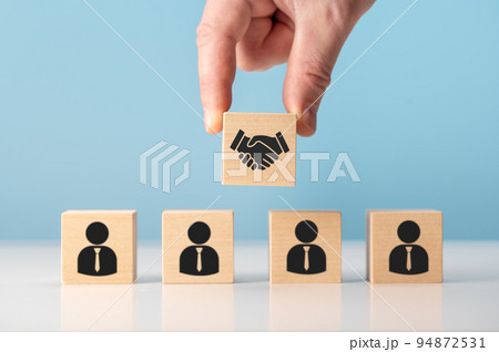 business contract. Hand putting hand shaking which print screen on wooden cube block in front of human icon for business deal and agreement concept. business contract. Hand putting hand shaking which print screen on wooden cube block in front of human icon for business deal and agreement concept. 94872531
