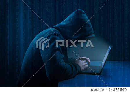 Hacker. Hacker using laptop on dark binary code digital background. Faceless hooded anonymous computer hacker. Hacking and malware concept. 94872699