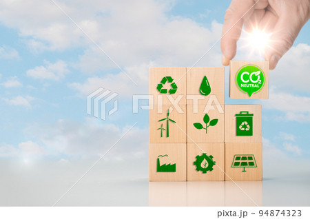 Net zero and carbon neutral concept. Put wooden cubes with green net zero icon. Hand put wooden cubes with green net zero icon and green icon on blue sky background. 94874323