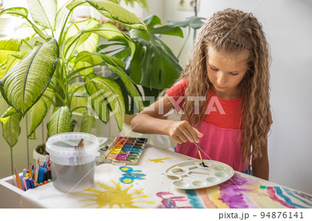 Laughing blonde curly little girl drawing paper art picture chalks sitting on near childish hovel Laughing blonde curly little girl drawing paper art picture chalks sitting on near childish hovel 94876141