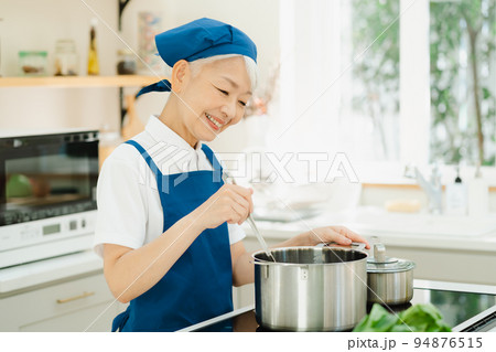 キッチンで料理をするハウスキーパーのシニア女性 94876515