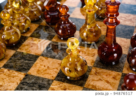Natural amber different chess pieces figures standing on brown stone board. Close up game concept competition, Classic Gambit Tournament of confrontation. Natural amber different chess pieces figures standing on brown stone board. Close up game concept competition, Classic Gambit Tournament of confrontation. 94876517