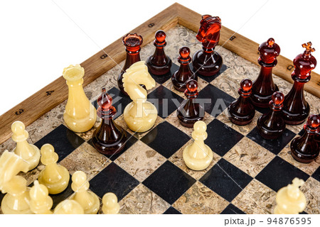 Natural amber different chess pieces figures standing on brown stone board. Close up game concept competition, Classic Gambit Tournament of confrontation. Natural amber different chess pieces figures standing on brown stone board. Close up game concept competition, Classic Gambit Tournament of confrontation. 94876595