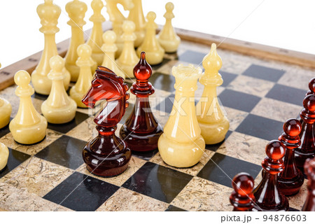 Natural amber different chess pieces figures standing on brown stone board. Close up game concept competition, Classic Gambit Tournament of confrontation. Natural amber different chess pieces figures standing on brown stone board. Close up game concept competition, Classic Gambit Tournament of confrontation. 94876603