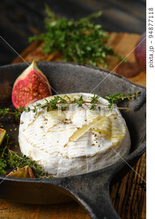 Closeup view of baked camembert cheese and figs ready for baking on frying pan 94877118