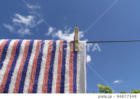 Clothes peg on a towel and washing line against a blue sky 94877349