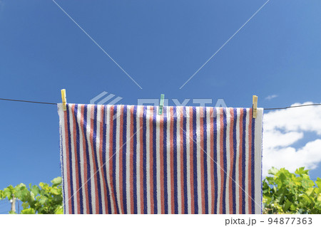 Clothes peg on a towel and washing line against a blue sky 94877363