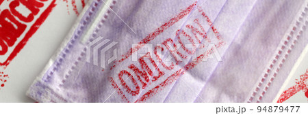Protective medical face mask with omicron virus infection stamp closeup Protective medical face mask with omicron virus infection stamp closeup 94879477