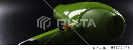 Green professional hairdryer device lay on black background, tool for beauty master 94879478