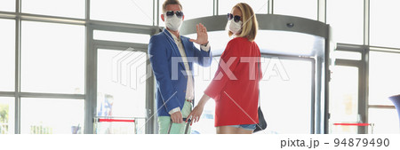 Couple dressed in luxury suits with suitcase wave goodbye before flying on vacation 94879490