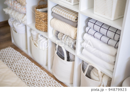 Neatly folded linen cupboard shelves storage at eco friendly straw basket placed closet organizer Neatly folded linen cupboard shelves storage at eco friendly straw basket placed closet organizer 94879923