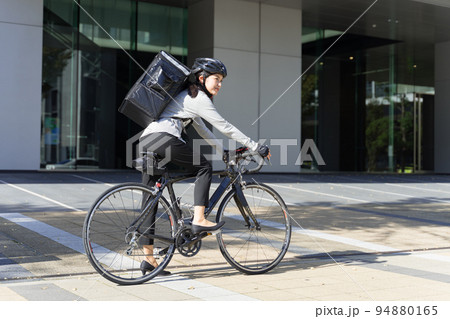 ロードバイクに跨っているフードデリバリー　女性配達員 94880165