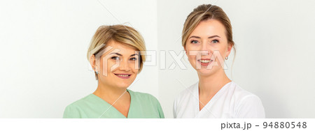 Close-up portrait of two young smiling female caucasian healthcare workers standing staring at the camera on white background Close-up portrait of two young smiling female caucasian healthcare workers standing staring at the camera on white background 94880548
