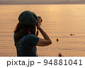 夕暮れ時の猪苗代湖を撮影する女性 94881041